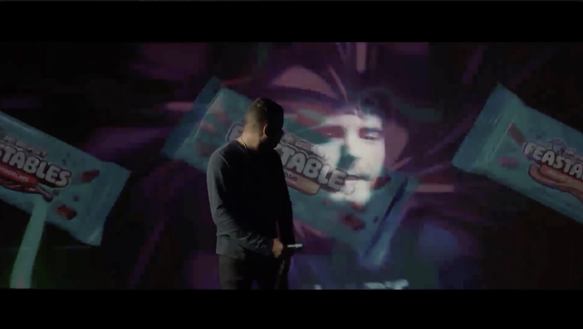 Cinematic Feastables commercial frame with a performer against colorful projected chocolate bars.